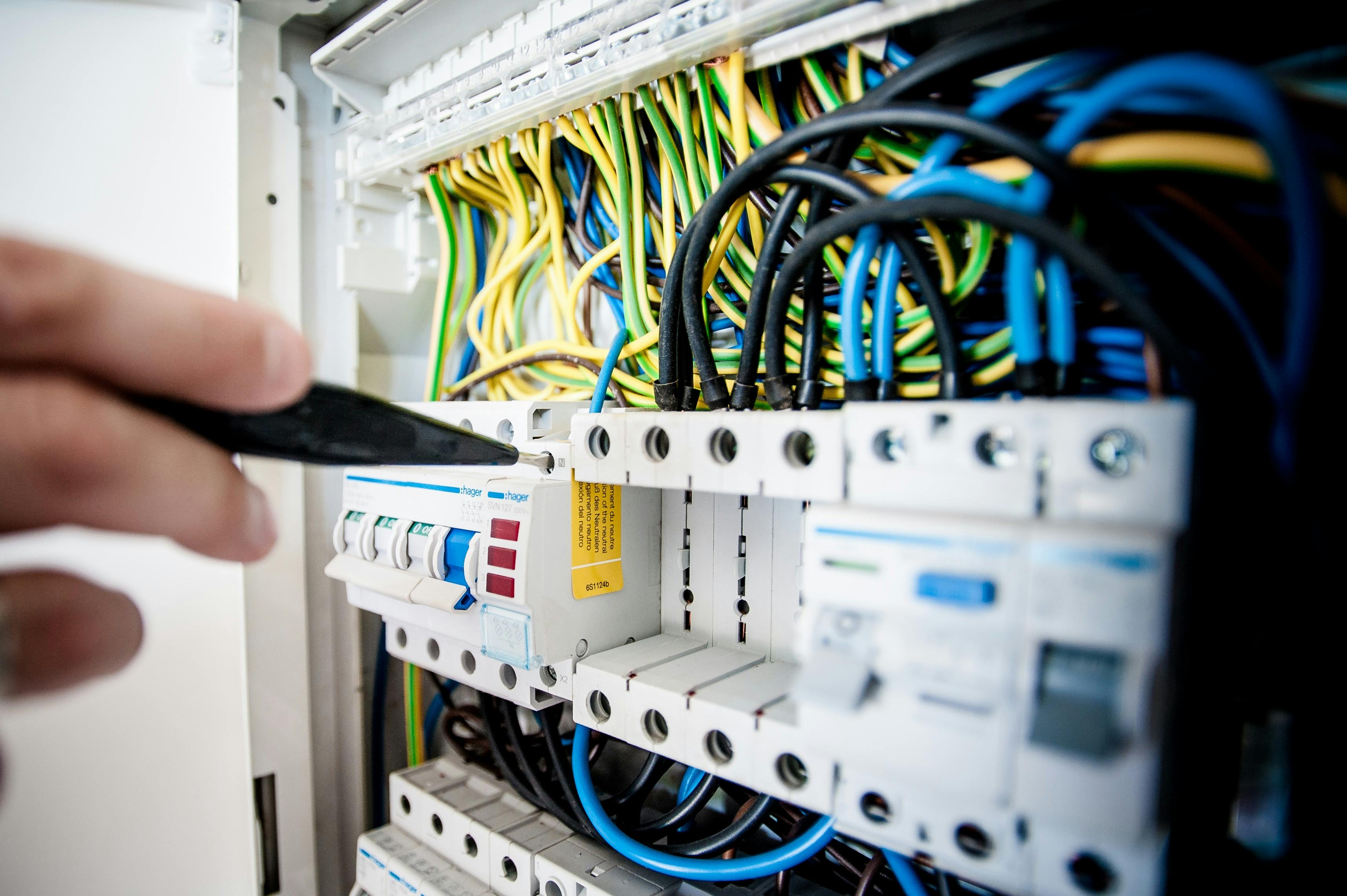 Technician working on an industrial electrical control panel with multicolored wires